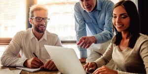 Beautiful business people are using a laptop, discussing affairs and smiling while working in office